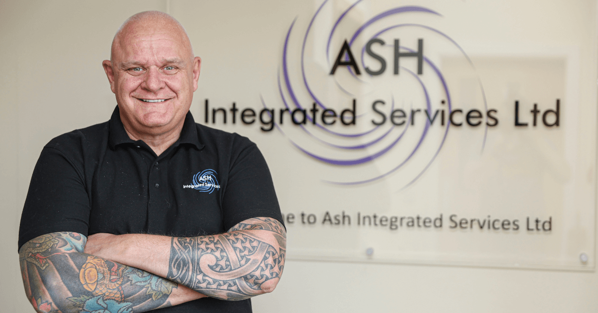 Gary Zetter from ASH Integrated Services stood in front of their logo on the wall at their offices