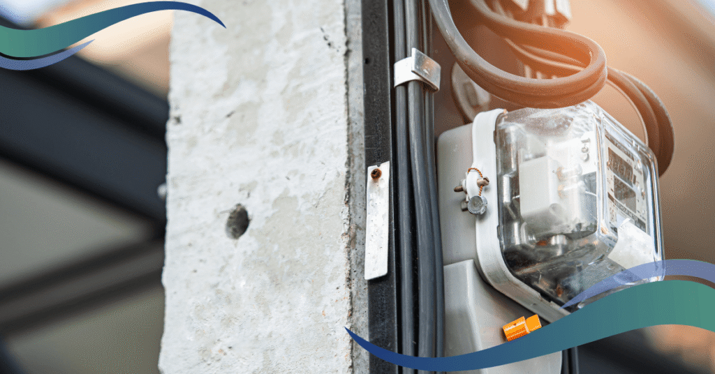 Close-up of an electrical meter attached to a concrete pole with black cables running alongside.