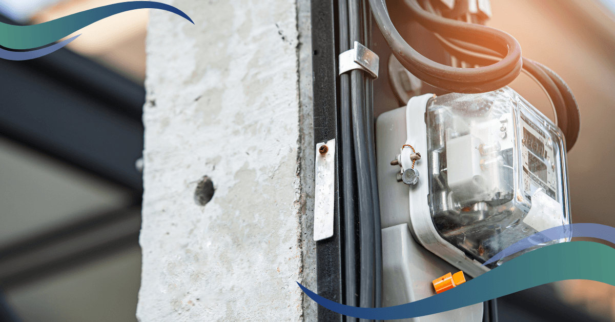 Close-up of an electrical meter attached to a concrete pole with black cables running alongside.