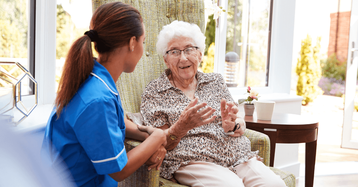 a nurse talking to an elderly person in a chair