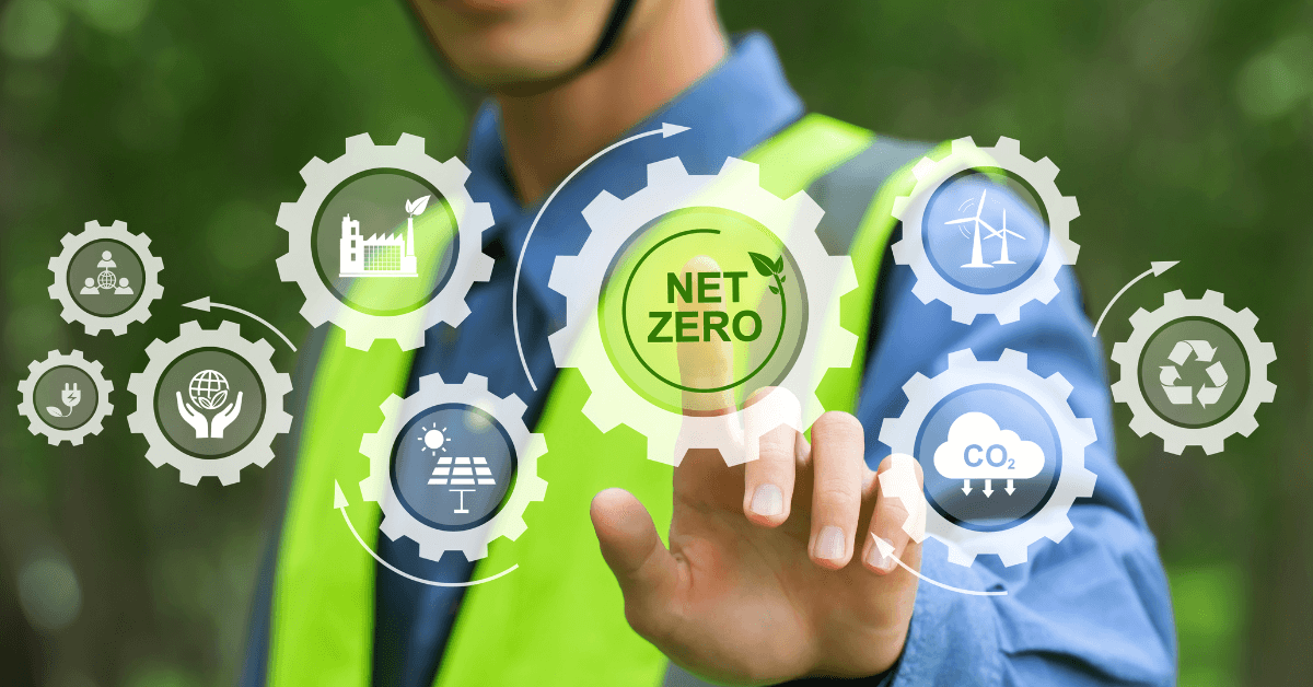 Image shows worker in high vis vest pointing at cogs on a screen depicting all the element of net zero