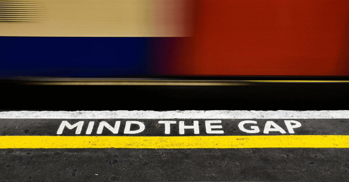 The mind the gap sign is on the platform at a train station