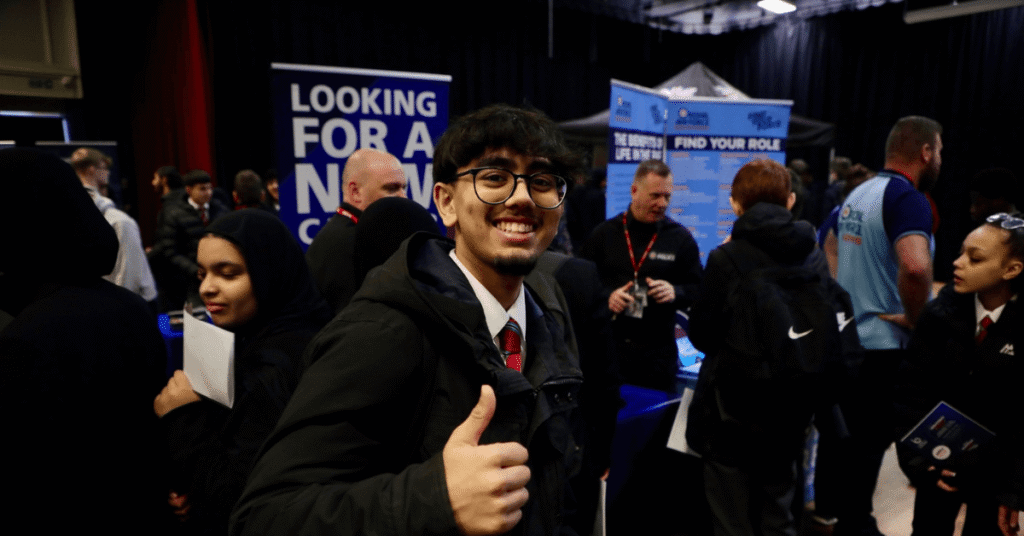 Image shows male student smiling, giving a thumbs up