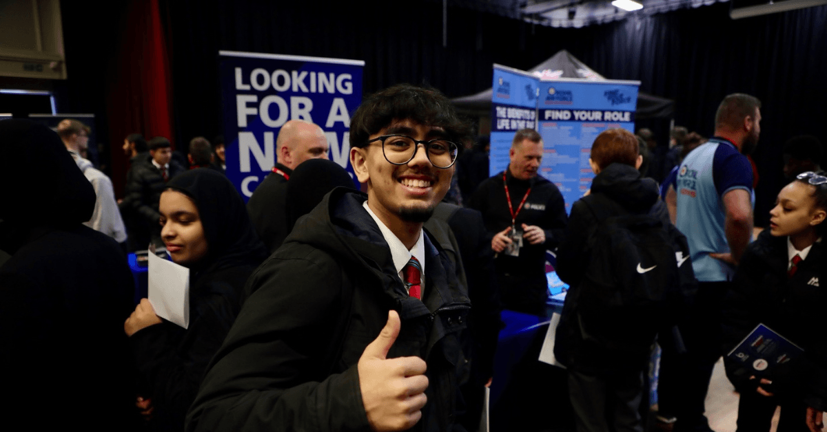 Image shows male student smiling, giving a thumbs up