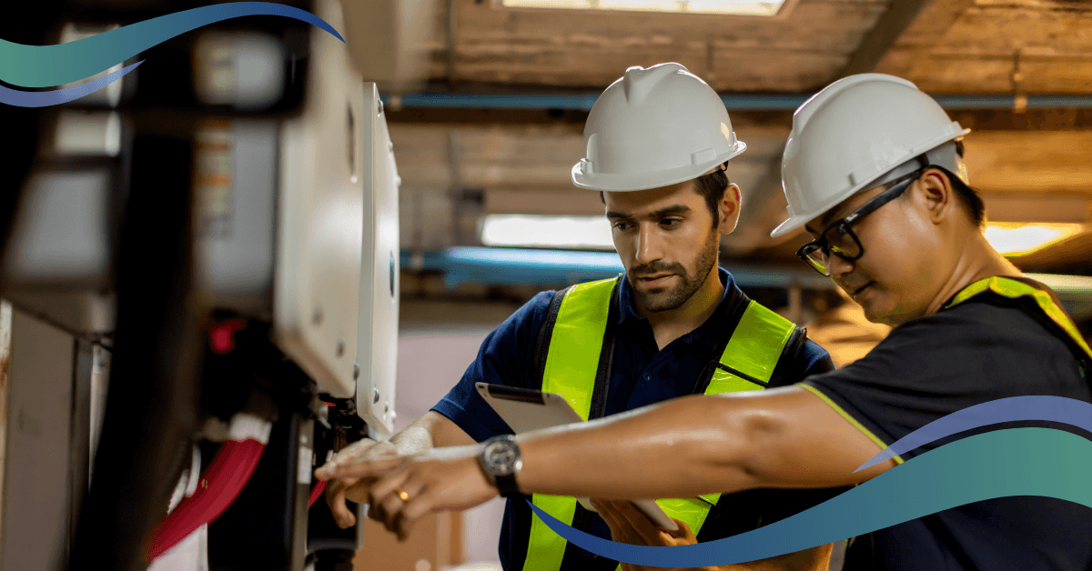 Two male workers in white hard hats talking