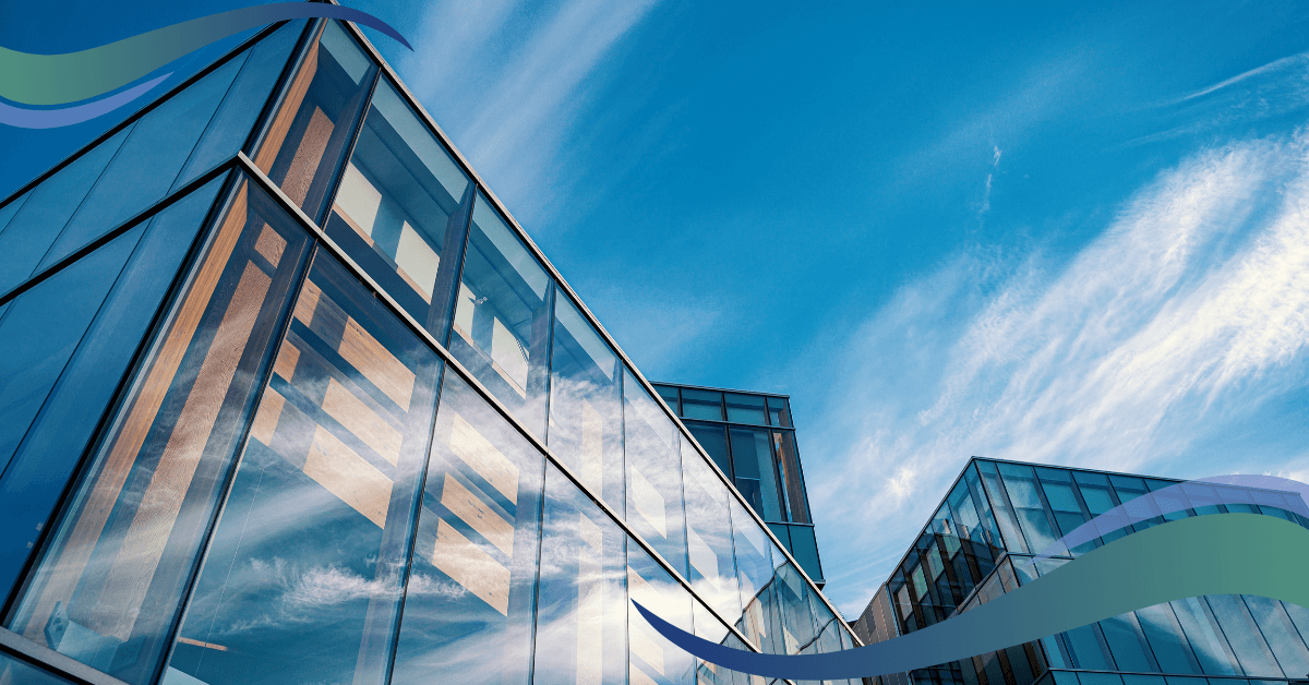 Modern glass buildings reflecting a bright blue sky with wispy clouds.