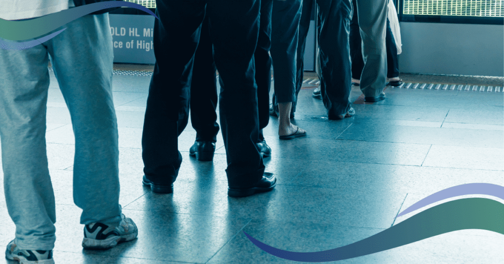 Image shows peoples legs waiting in line